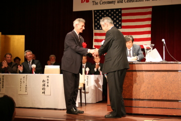 記念式で握手を交わすアルブリトン副市長と松浦市長の写真